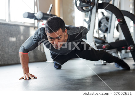 Sportsman doing one arm push-ups Sportsman doing one arm push-ups 57002631