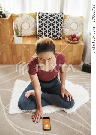 Young woman using yoga app 57002758