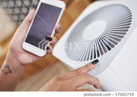 Woman turning on air conditioner Woman turning on air conditioner 57002759
