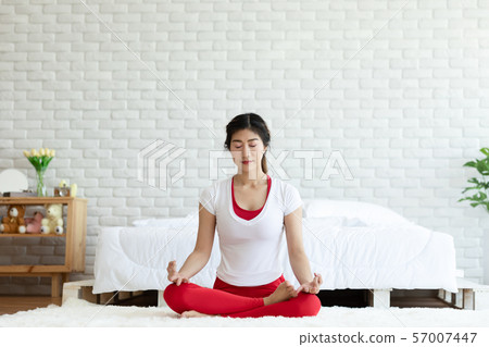 Attractive Asian woman practice yoga lotus pose to meditation in bedroom after wake up in the morning Feeling so comfortable and relax,Healthcare Concept Attractive Asian woman practice yoga lotus pose to meditation in bedroom after wake up in the morning Feeling so comfortable and relax,Healthcare Concept 57007447