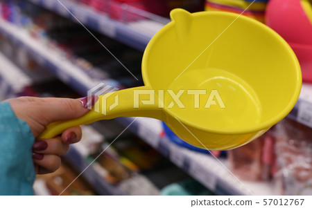 Plastic bucket for water in female hand on shop background 57012767