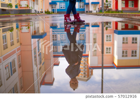 Reflection of a girl in a puddle and houses, park Reflection of a girl in a puddle and houses, park 57012916