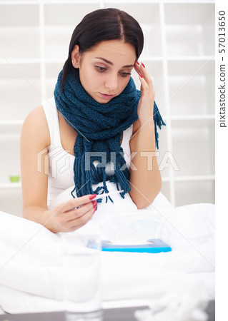 Woman with thermometer sick colds, flu, fever, headache in bed 57013650