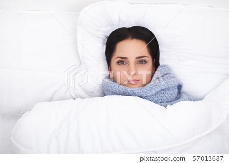 Sick Woman. Flu. Girl with cold lying under a blanket holding a tissue Sick Woman. Flu. Girl with cold lying under a blanket holding a tissue 57013687