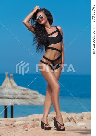 Happy woman on the beach. Portrait of the beautiful girl close-up, the wind fluttering hair. Spring 57013763