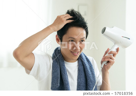 Young Japanese man drying her hair with a dryer 57018356