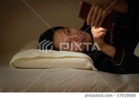 Japanese male watching the smartphone before going to bed Dim light Japanese male watching the smartphone before going to bed Dim light 57019006