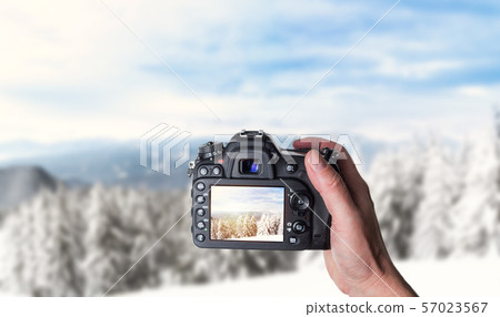 Man taking photo of  in winter snowy mountains 57023567