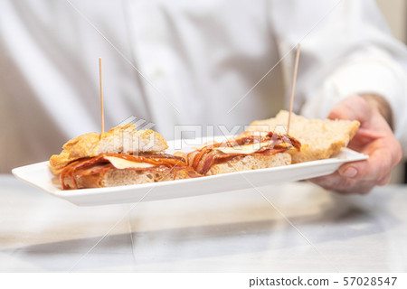 Chef preparing delicious typical Spanish food, bacon tapa or Pintxo of bacon. Chef preparing delicious typical Spanish food, bacon tapa or Pintxo of bacon. 57028547