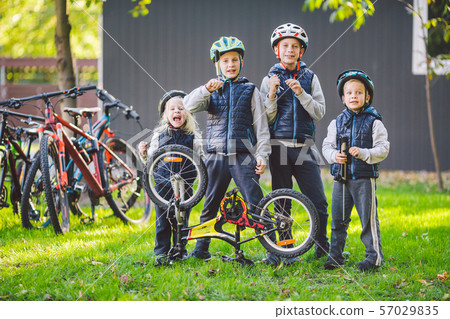 Children mechanics, bicycle repair. Happy kids fixing bike together outdoors in sunny day. Bicycle Children mechanics, bicycle repair. Happy kids fixing bike together outdoors in sunny day. Bicycle 57029835