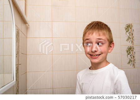 Smiling scholboy looks in the bathroom mirror. Smiling scholboy looks in the bathroom mirror. 57030217