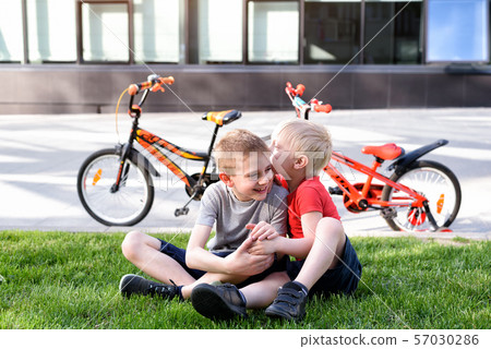 Two boys communicate sitting on the grass. Rest 57030286