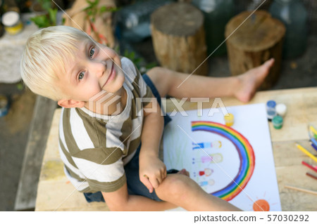 Cute boy draws rainbow and family. Open air. Top Cute boy draws rainbow and family. Open air. Top 57030292