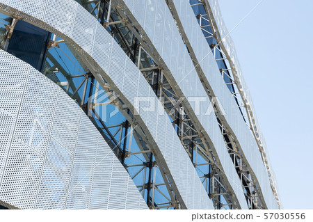 Low angle view of high modern building construction with metal perforated panel with round holes in Low angle view of high modern building construction with metal perforated panel with round holes in 57030556