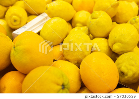 Fresh bright yellow lemons in wooden boxes at farmer's market or grocery store close-up. May be used 57030559