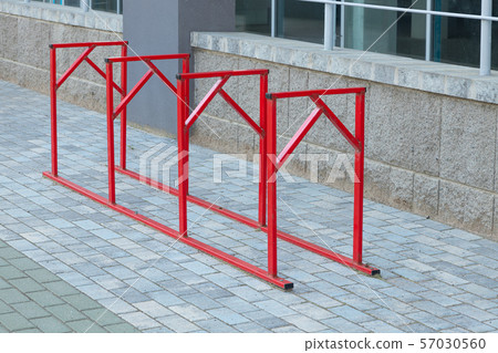 Red steel or iron parking place for bicycles standing on gray pavement by office or apartment Red steel or iron parking place for bicycles standing on gray pavement by office or apartment 57030560