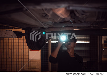 Lonely Asian male shining flashlight to examine 57030765