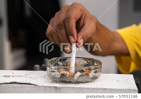 Hand putting out cigarette and destroy in ashtray Hand putting out cigarette and destroy in ashtray 57031186