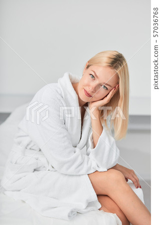 young awesome smiling woman in white bathrobe sitting in spa center on couch young awesome smiling woman in white bathrobe sitting in spa center on couch 57036768