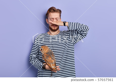 man in striped jumper closing his nose with finger because his bird stinking man in striped jumper closing his nose with finger because his bird stinking 57037561