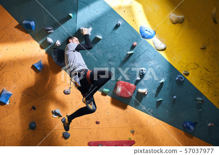 Young athletic sportsman has dynamic training in bouldering gym Young athletic sportsman has dynamic training in bouldering gym 57037977