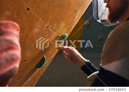 Close up view of unrecognizable climber with beard fixing artificial rock 57038043