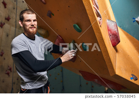 Motivated climber checking holds and rocks at artificial climbing wall Motivated climber checking holds and rocks at artificial climbing wall 57038045