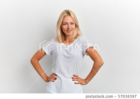 attractive woman in a white T-shirt with hands on the hips looking at the camera 57038397