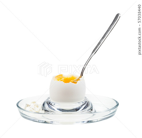 side view of open egg with spoon in glass egg cup 57038440