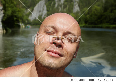 Butterfly on the nose of a bald man. 57039423
