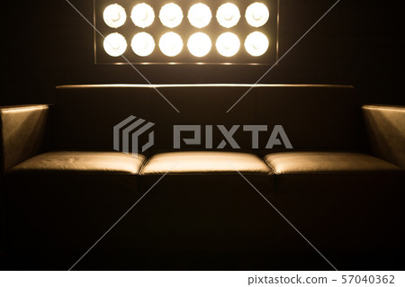 Brown sofa in a dark room. Light falls behind a stand with light bulbs. 57040362