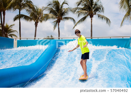 Teenager boy surfing in beach wave simulator Teenager boy surfing in beach wave simulator 57040492