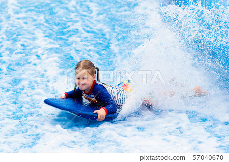 Little girl surfing in beach wave simulator Little girl surfing in beach wave simulator 57040670