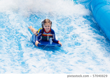 Little girl surfing in beach wave simulator Little girl surfing in beach wave simulator 57040829