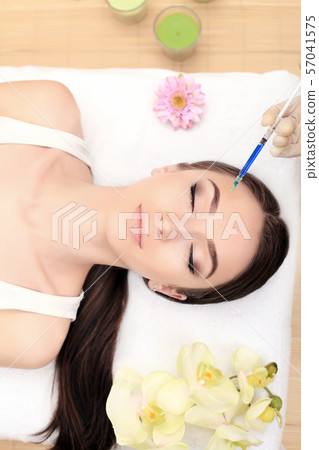 Hands of cosmetologist making injection in face, lips. Young woman gets beauty facial injections in 57041575