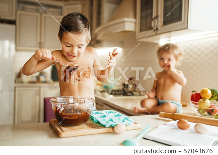 Little kids tastes melted chocolate on the kitchen 57041676