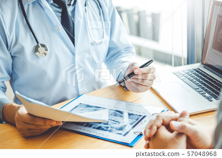 Dentist talking to male patient and presenting Dentist talking to male patient and presenting 57048968
