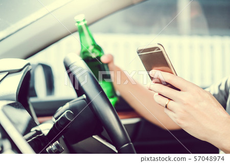 Drunk man driving a car on the road holding bottle Drunk man driving a car on the road holding bottle 57048974