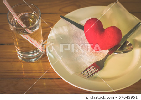 A little heart pillow on a dish with fork and spoon on table in restaurant A little heart pillow on a dish with fork and spoon on table in restaurant 57049951