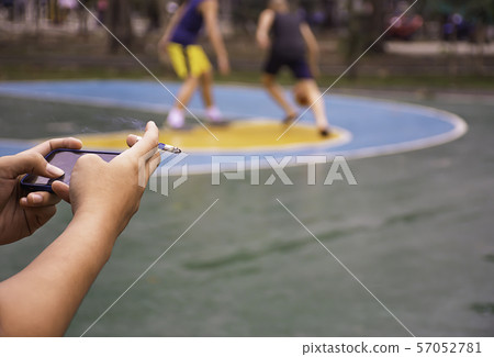 Hand holding a cigarette and a telephone. Background on basketball court Hand holding a cigarette and a telephone. Background on basketball court 57052781