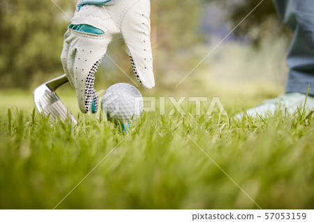 Hand in glove placing golf ball on tee Hand in glove placing golf ball on tee 57053159