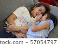 Mother and daughter laying on sofa and talking 57054797