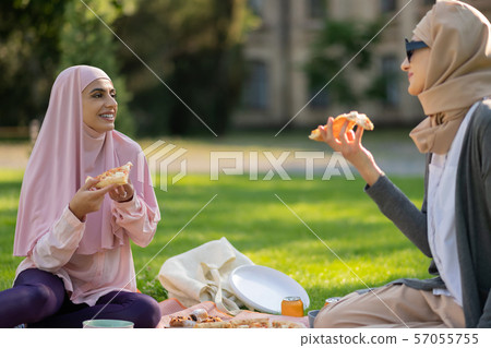 Muslim students eating pizza and talking after classes Muslim students eating pizza and talking after classes 57055755