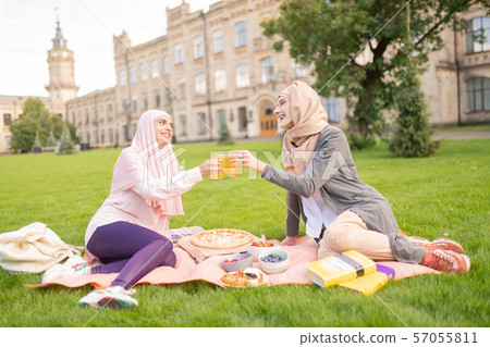 Muslim students having nice lunch break outside near university Muslim students having nice lunch break outside near university 57055811