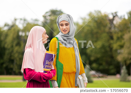 Muslim student wearing yellow dress talking to friend 57056070