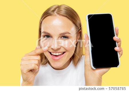 Caucasian young woman's half-length portrait on yellow background Caucasian young woman's half-length portrait on yellow background 57058785