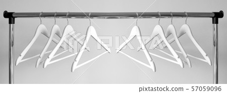 Empty clothes hangers on metal rail against grey Empty clothes hangers on metal rail against grey 57059096