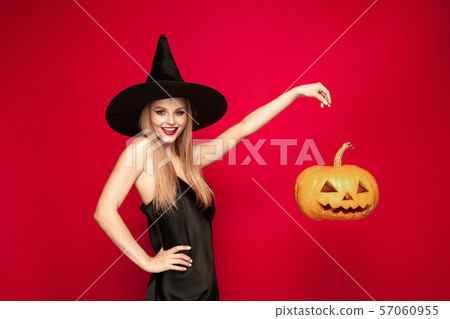 Young woman in hat as a witch on red background 57060955
