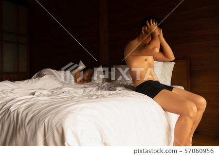 Man exercise sit ups in bed after wake up with his wife sleeping behind. 57060956