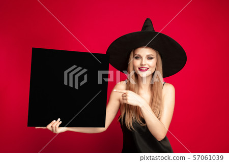 Young woman in hat as a witch on red background 57061039